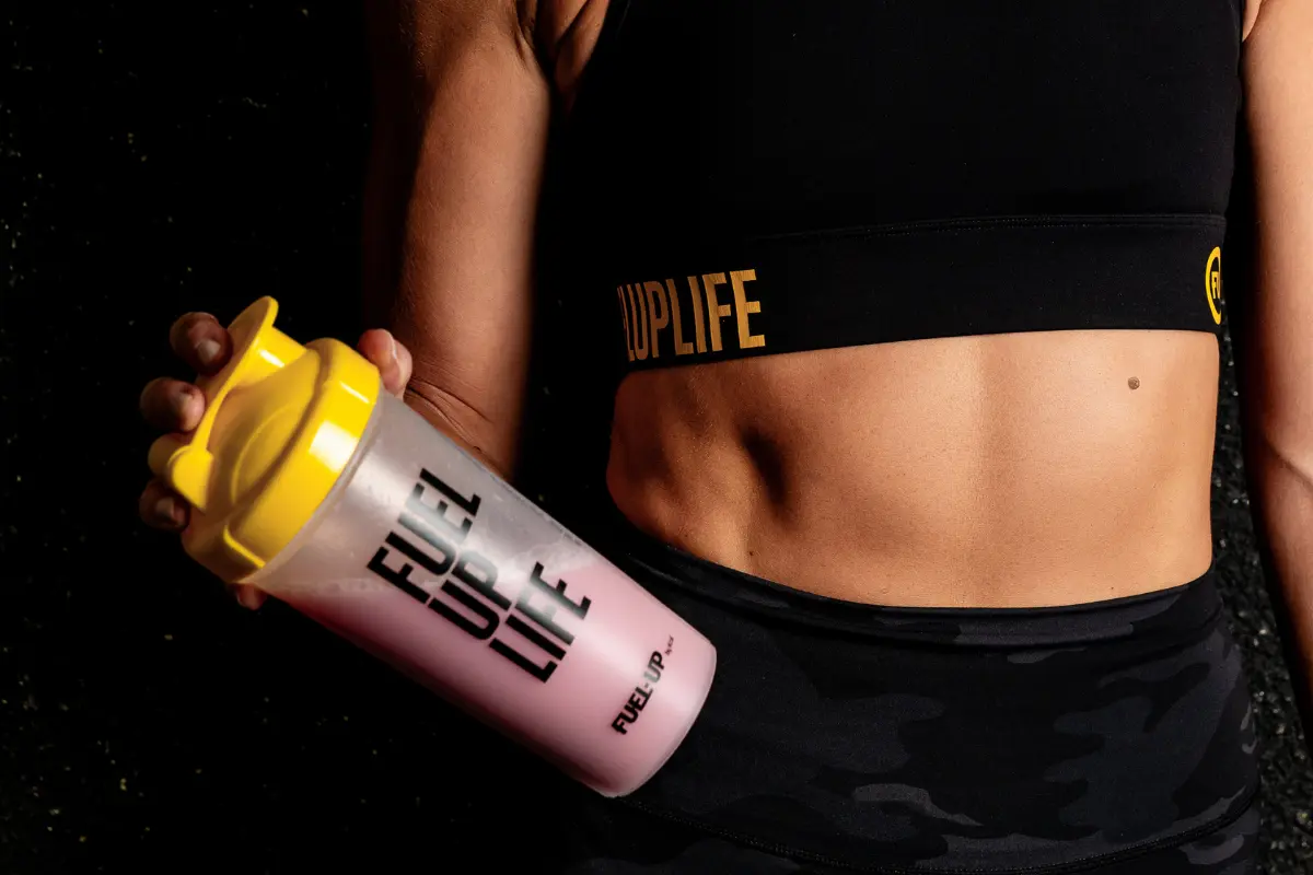 Woman in sports bra holding protein shake