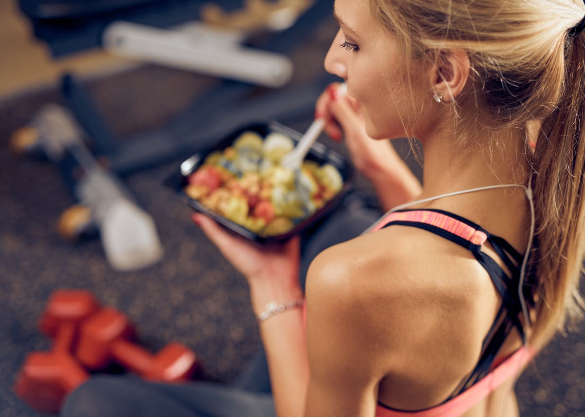 Woman eating her first meal early in the morning after a gym session