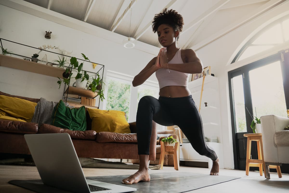 Woman working out from home doing split lunges
