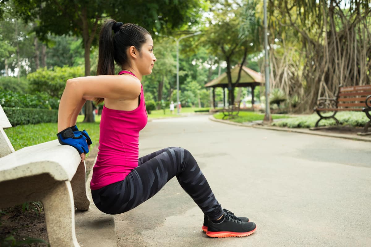 Woman using a bench for tricep dips